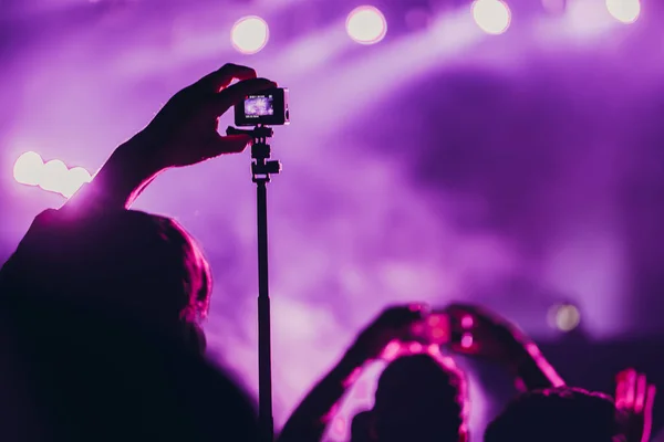 Stage lights and crowd of audience with hands raised at a music festival. Fans enjoying the party vibes.