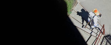 Profesyonel dezenfektan işçisi ekibi, koronavirüs salgını nedeniyle merdivenleri spreylerken koruyucu maske takıyor.. 