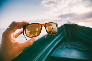 Günbatımı, tekne ve güneş gözlüklü seyahat ve seyahat tutkusu konsepti. Gözlüklerdeki turist yansıması. 