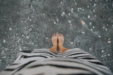 Denizdeki siyah kumların üzerinde çıplak ayakla duruyorum.. 