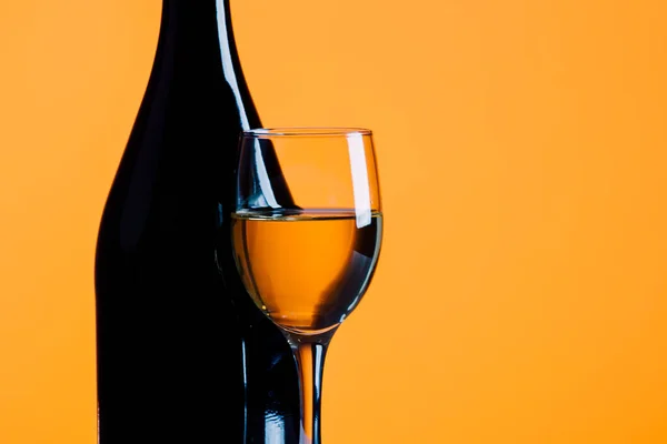 wine bottle and glass on a yellow background