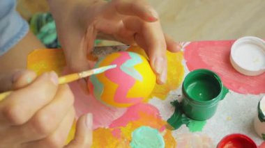 hands of the artist who paints the easter egg. The girl paints an egg. Easter decoration preparing happy easter