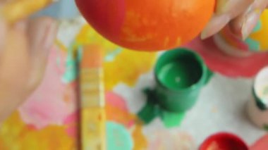 Posting: the hand dips the brush into the paint and draws stripes on the Easter egg. Girl draws a striped pattern on an egg. Easter decoration preparing happy easter