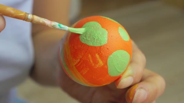 Handen målar ett påskägg med pensel och sätter på ett stativ. Flickan ritar ett randigt mönster på ett ägg. Påsk dekoration, förberedelse för glad påsk — Stockvideo