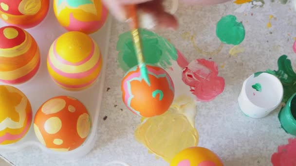 Mãos do artista que pinta o ovo de Páscoa. A menina pinta um ovo em um fundo colorido de ovos de Páscoa. Decoração de Páscoa preparar páscoa feliz — Vídeo de Stock