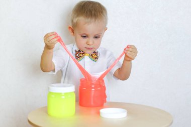 Küçük çocuk oyun masasında sümükle oynuyor, küçük çocuklarda iyi motor becerileri geliştirmek için harika bir aktivite. 