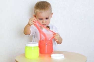 Küçük çocuk oyun masasında sümükle oynuyor, küçük çocuklarda iyi motor becerileri geliştirmek için harika bir aktivite. 