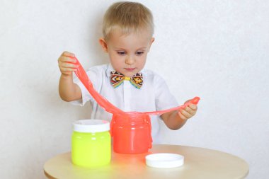 Küçük çocuk oyun masasında sümükle oynuyor, küçük çocuklarda iyi motor becerileri geliştirmek için harika bir aktivite. 
