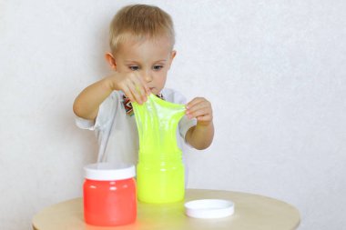 Küçük çocuk oyun masasında sümükle oynuyor, küçük çocuklarda iyi motor becerileri geliştirmek için harika bir aktivite. 