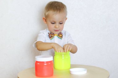 Küçük çocuk oyun masasında sümükle oynuyor, küçük çocuklarda iyi motor becerileri geliştirmek için harika bir aktivite. 