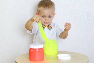 Küçük çocuk oyun masasında sümükle oynuyor, küçük çocuklarda iyi motor becerileri geliştirmek için harika bir aktivite. 