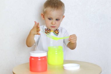 Küçük çocuk oyun masasında sümükle oynuyor, küçük çocuklarda iyi motor becerileri geliştirmek için harika bir aktivite. 