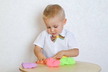 2 yaşındaki küçük çocuk kinetik modelleme kiliyle, plastikle, oyun hamuruyla oynuyor. Küçük çocuklarda iyi motor becerileri geliştirmek için eğlenceli bir aktivite. 