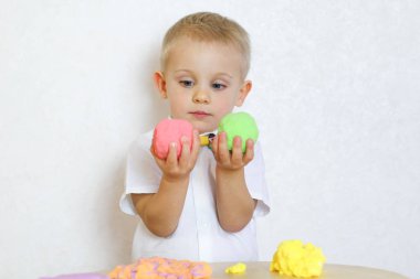 2 yaşındaki küçük çocuk kinetik modelleme kiliyle, plastikle, oyun hamuruyla oynuyor. Küçük çocuklarda iyi motor becerileri geliştirmek için eğlenceli bir aktivite. 