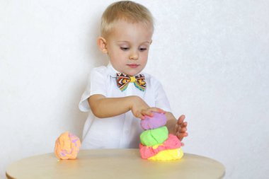 2 yaşındaki küçük çocuk kinetik modelleme kiliyle, plastikle, oyun hamuruyla oynuyor. Küçük çocuklarda iyi motor becerileri geliştirmek için eğlenceli bir aktivite. 