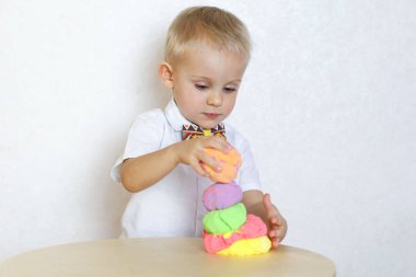 2 yaşındaki küçük çocuk kinetik modelleme kiliyle, plastikle, oyun hamuruyla oynuyor. Küçük çocuklarda iyi motor becerileri geliştirmek için eğlenceli bir aktivite. 