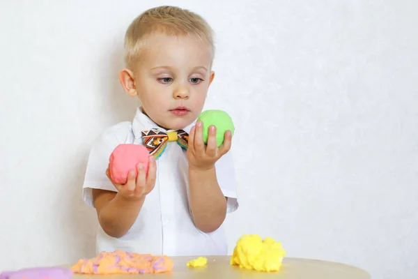 2 yaşındaki küçük çocuk kinetik modelleme kiliyle, plastikle, oyun hamuruyla oynuyor. Küçük çocuklarda iyi motor becerileri geliştirmek için eğlenceli bir aktivite. 