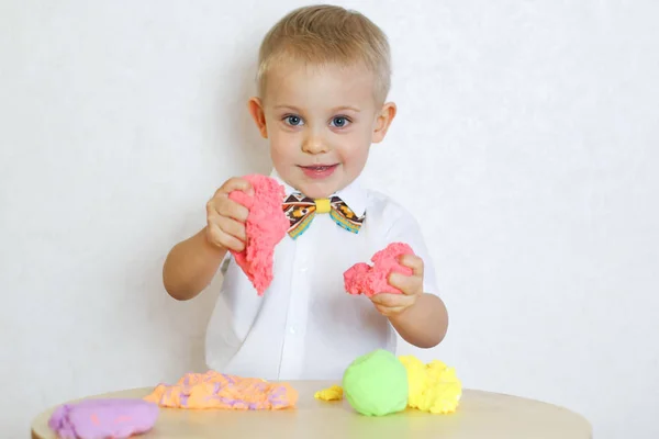 2 yaşındaki küçük çocuk kinetik modelleme kiliyle, plastikle, oyun hamuruyla oynuyor. Küçük çocuklarda iyi motor becerileri geliştirmek için eğlenceli bir aktivite. 