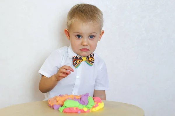 angry toddler playing with kinetic modeling clay, plasticine, unhappy and about to start a tantrum