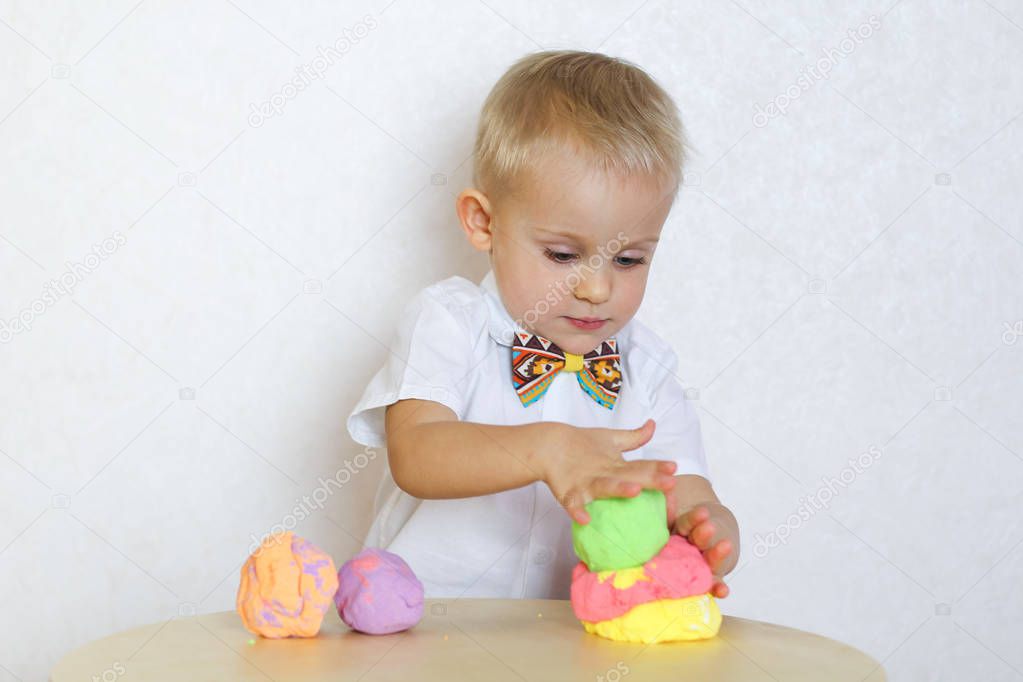 2 year old toddler boy is playing with kinetic modeling clay, plasticine, play-dough, a fun activity to develop fine motor skills in young children 