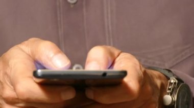 Erkekler parmaklarını dokunmatik ekranlı akıllı telefona basıyor, akıllı telefonu yakın planda kullanıyor.
