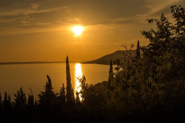 Gölün üzerinde günbatımı, sarı gökyüzü, orman ve su