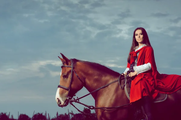 Schöne Prinzessin mit rotem Umhang auf einem Pferd — Stockfoto
