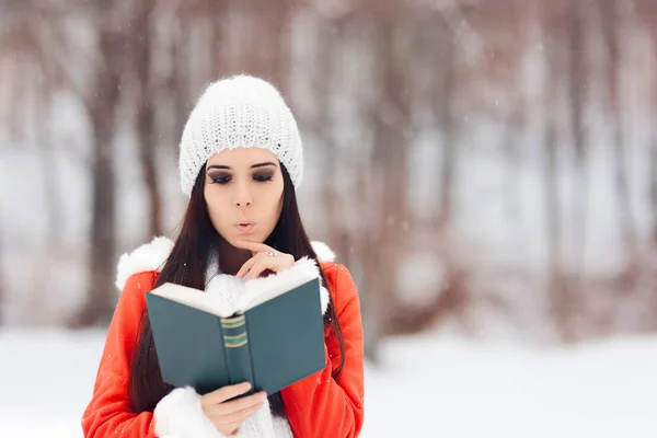 Mulher surpresa lendo um livro fora na neve — Fotografia de Stock