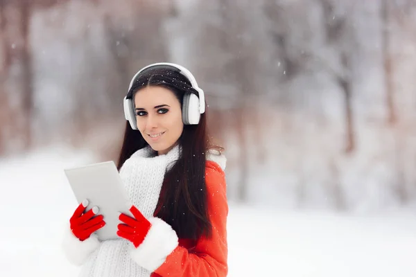 Счастливая зимняя девочка с наушниками и компьютером — стоковое фото