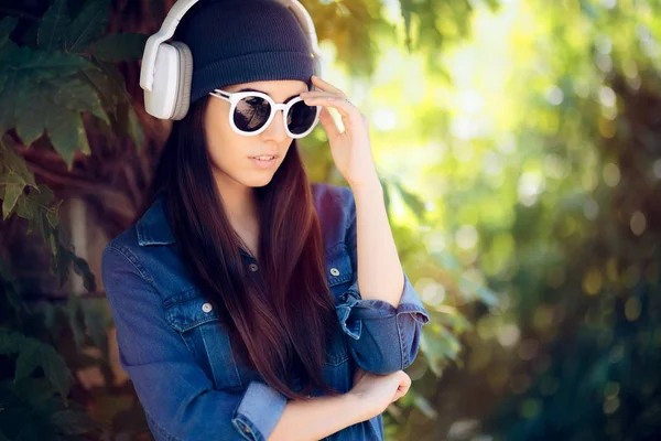 サングラスは彼女のヘッドフォンで音楽を聴くとデニムのファッションの女の子 — ストック写真