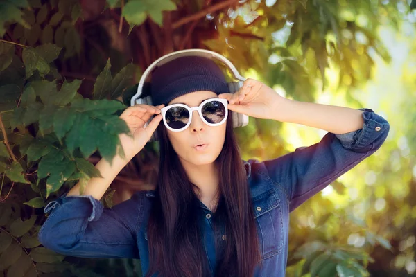 Sorprendida Denim Fashion Girl con gafas de sol escuchando música en sus auriculares —  Fotos de Stock