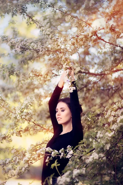 Mulher graciosa bonita na flor da primavera que gosta das flores — Fotografia de Stock