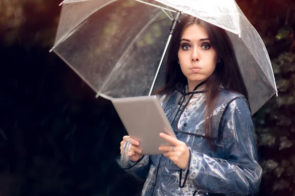 滑稽的雨衣和伞拿着 Pc 平板电脑的女人 — 图库照片