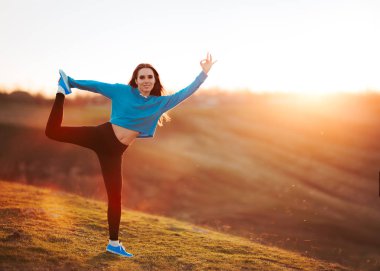 Doğada günbatımında germe mutlu uygun kadın