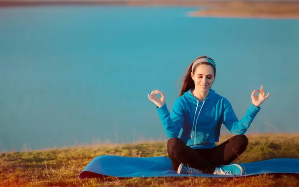 Szczęśliwa dziewczyna medytuje na matę do jogi w przyrodzie — Zdjęcie stockowe