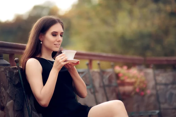 Elegant kvinde drikker kaffe i haven - Stock-foto