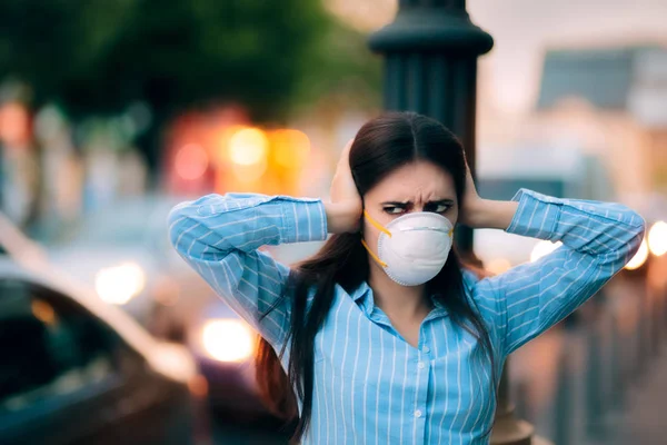 Chica con máscara cubriendo sus oídos debido a la contaminación acústica — Foto de Stock