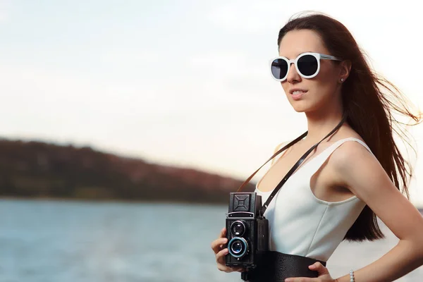 Mujer retro con cámara de fotos vintage en una playa — Foto de Stock
