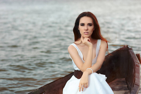 Thoughtful Woman in White Dress Sitting in an Old Boat 
