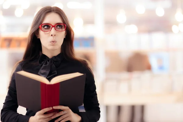 Garota engraçada lendo um livro na frente de uma estante — Fotografia de Stock