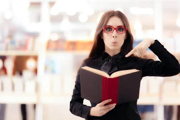 Garota engraçada lendo um livro na frente de uma estante — Fotografia de Stock