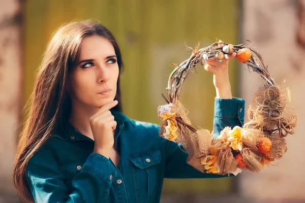 Ragazza pensante che tiene corona d'autunno decorativa — Foto Stock