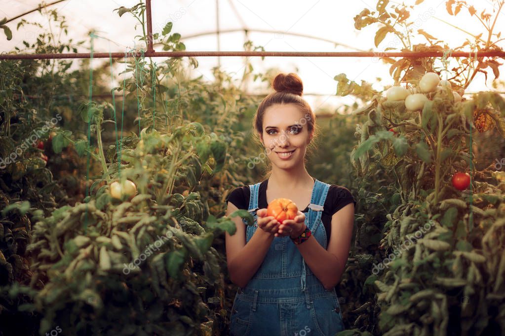 Happy Farm Girl Holding a Tomato inside a Greenhouse