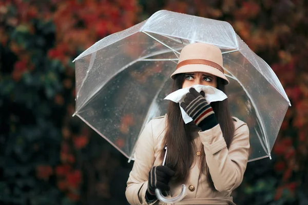 Mujer enferma sosteniendo paraguas bajo la lluvia otoñal sonándose la nariz — Foto de Stock