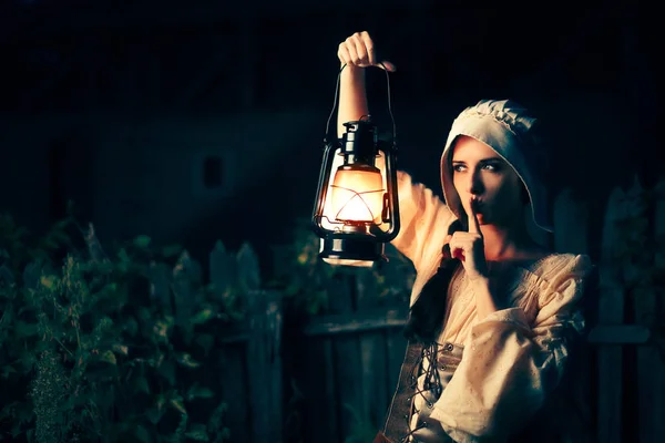 Středověká žena s prstem na rtech drží lampu — Stock fotografie