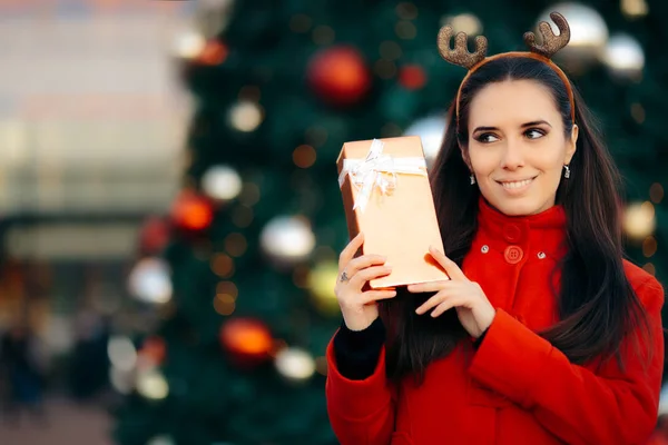 Nő gazdaság díszdobozban díszített karácsonyfa előtt — Stock Fotó