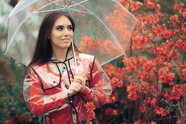 Beautiful Woman with Transparent Raincoat and Umbrella Enjoying Rain