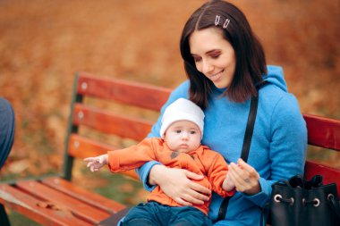 Anne ve bebek parkta bir bankta oynuyorlar.