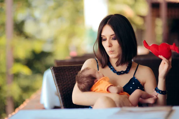 Mother Holding Toy Calming her Crying Baby in a Restaurant