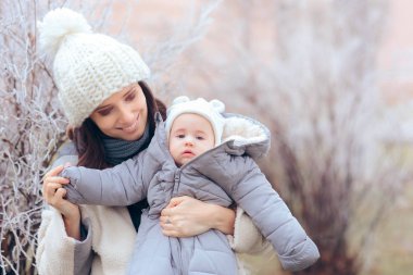 Anne, bebeği kışın yürüyüşe çıkarıyor. 